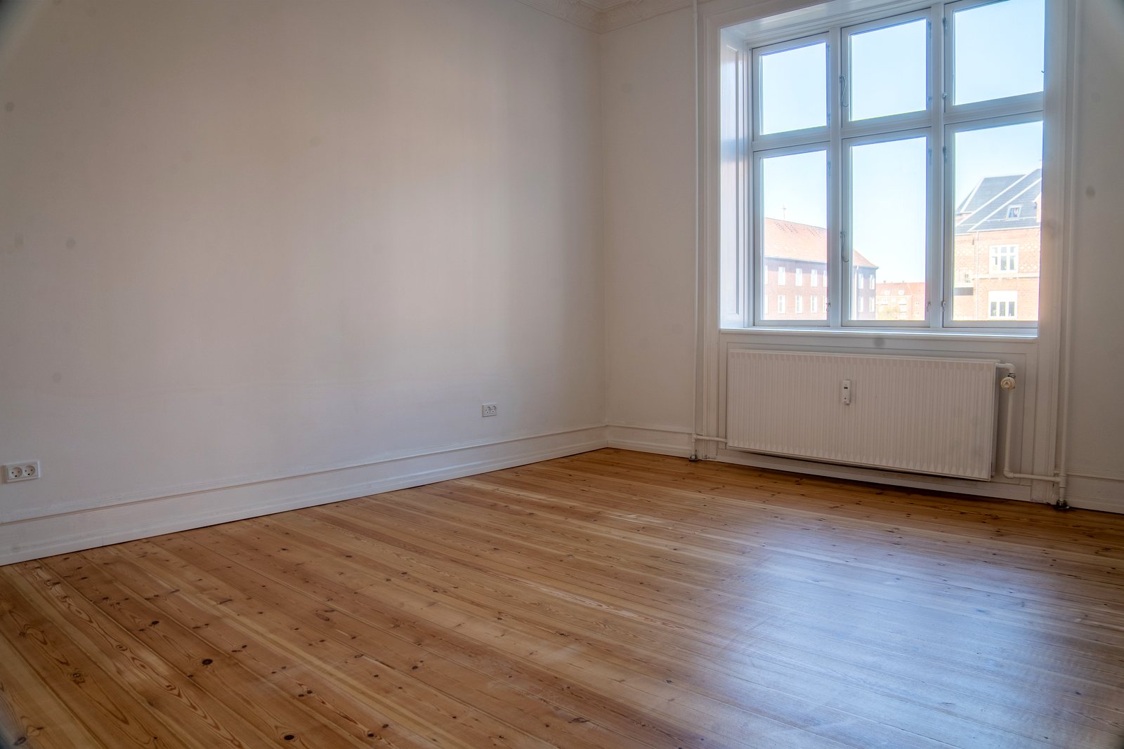 Værelse med vindue, radiator og afslebet plankegulv