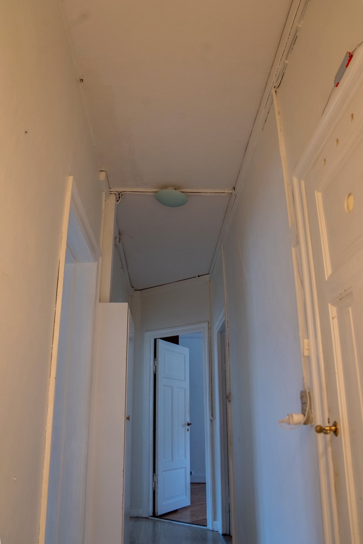 Den smalle gang med synlige kabler og lappet loft før renovering
